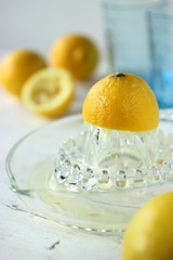 Mezzo limone in primo piano e vari limoni e bicchieri blu sullo sfondo