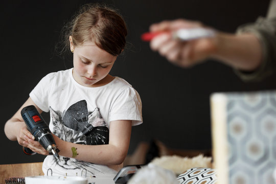 Young girl working with drill in workshop
