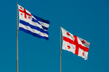 Large waving flag autonomous republic of Adjara and flag of Georgia, also known as the Five Cross Flag against the blue sky, Batumi, Adjara, Georgia