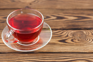 Full cup of red tasty raspberry tea on old wooden rustic table
