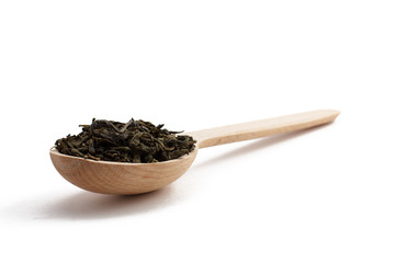 Wooden spoon with dry leaves of green tea with isolated background