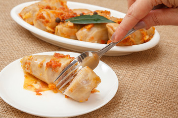 Female hand holding a fork and going to taste homemade cabbage rolls stuffed with rice and meat