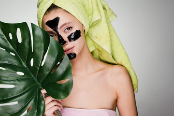 a laughing young girl with a green towel on her head applied a black mask to the problem areas on...