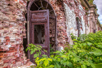 Fototapeta na wymiar The building is overgrown with grass. Buildings with destroyed walls. Broken doors in an old building. The city of Kronstadt. Russia. Forts in Kronstadt. The Gulf of Finland.
