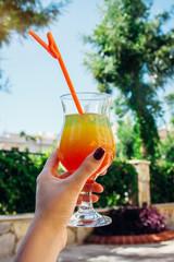 Woman holds an exotic cocktail outside the hotel