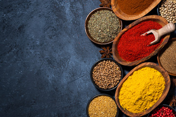 paprika, turmeric, red pepper and other oriental spices on dark background, top view