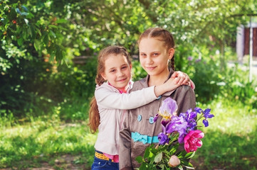 Fototapeta premium Two children, girls, sisters are a bouquet of spring flowers on the background of the spring garden.
