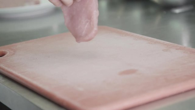 Raw pork placed on cutting board, slow motion