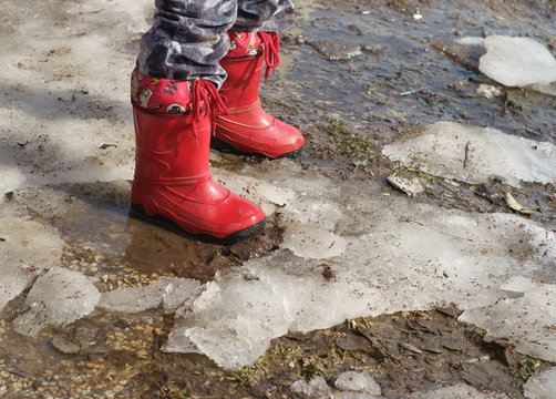 Child's legs in red boots in spring