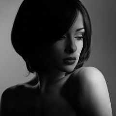 Beautiful makeup woman with thinking sad look and short hair style, red lipstick on dark shadow background. Closeup portrait. Black and white. Art