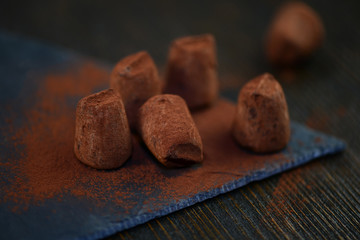 Pralinen auf dunkler Schokolade Trüffel auf Schiefertafel mit Kakao