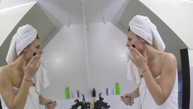 Skin care. Woman applying clay mud mask to her face in her bathroom.