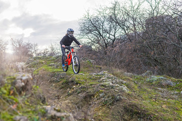 Cyclist riding a mountain bike on rocks, downhill.