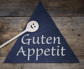 Schiefertafel Dreieck mit Text Guten Appetit und Kochlöffel aus Holz Smiley - obrazy, fototapety, plakaty