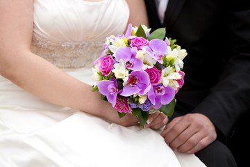 Букет невесты из фиолетовых или сиреневых орхидей, ярко-розовых роз, белых цветов и бутонов и зелени