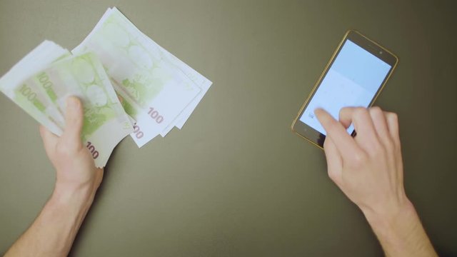 Top view. Male hands count money and summarize the result on the calculator.