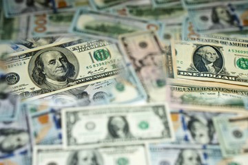 two bills of ont hundred dollars and one dollar is clearly distinguished against the background blurry banknotes