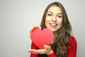 Portrait of a sweet perfect girl smiling at camera with heart shaped paper in her hands. Valentine's Day concept.