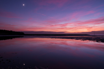 Fototapeta na wymiar Purple sunset on the beach with wonderfull reflection in water