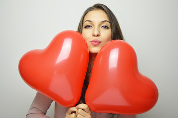 Lovely girl with Valentine heart balloons make air kiss and looking at the camera. Sweet young woman with two heart shaped balloons on white background. Valentine's day concept.