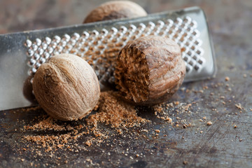 Making nutmeg powder process. Nuts silver grater. Kitchen still life photo. Shallow depth of field, aged brown rusty background. Selective focus