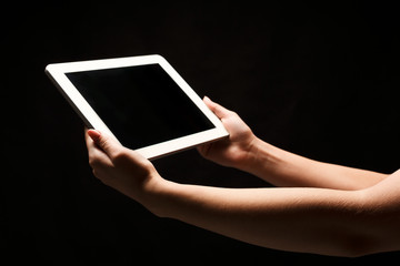 Woman holding tablet with blank screen at black background
