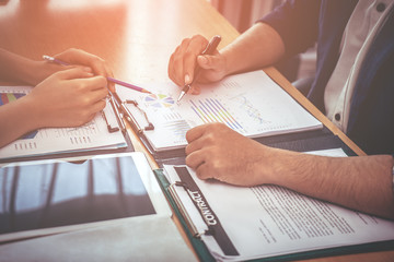 Two business worker are consulting on company data document on table