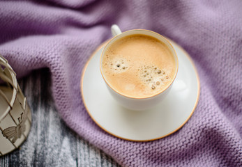 Cup of coffee and sweater on a wooden background