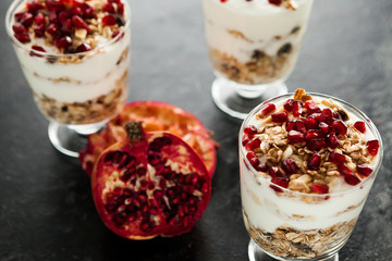Close up on healthy home-made muesli with pomegranate on dark wooden background