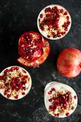 Top view on dessert with yoghurt and pomegranate on dark wooden background