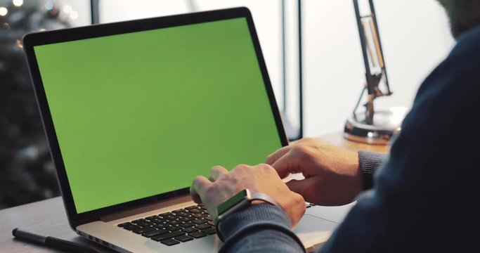 Businessman using laptop with green screen, male hands typing text or message. Surfing the Internet, programming, messaging. Successful lifestyle. Close up view