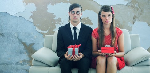Composite image of unsmiling geeky couple with gift