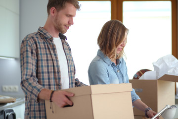 Couple unpacking cardboard boxes in their new home. Young couple.