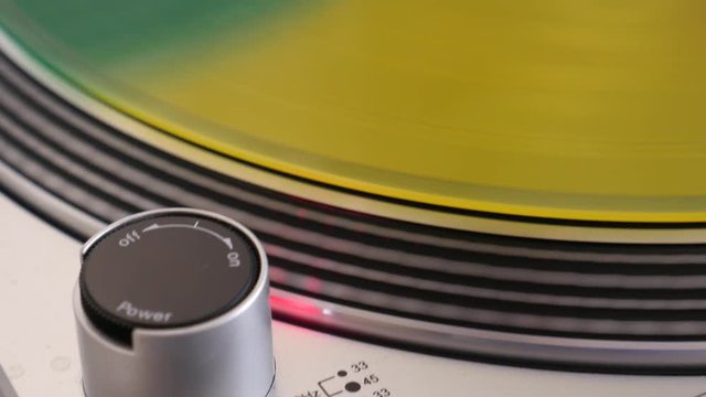 motley vinyl spinning on a record player, red yellow greens vinyl records close-up
