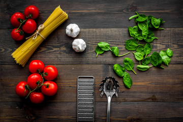 Main ingredients for italian pasta. Spaghetti, tomatoes, garlic, green basil on dark wooden background top view