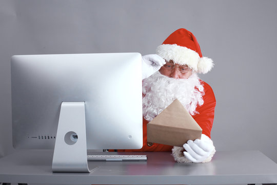 Santa Claus reading children letters and writing responses to them using laptop .