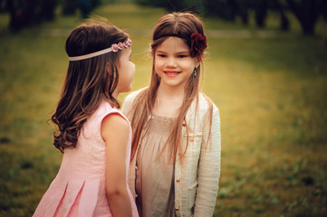 two happy kid girlfriends playing together in spring or summer park