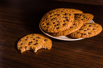 Plate with chocolate chip cookies on a dark wooden table