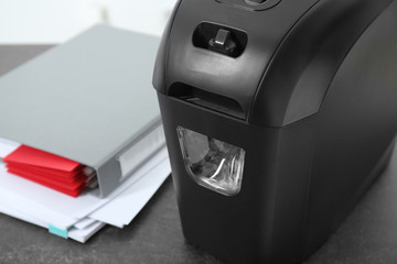Document shredder and papers on table, closeup