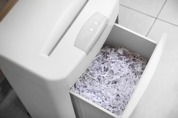Document shredder with paper shreds indoors,closeup