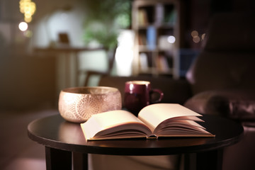 Stylish table with open book in living room