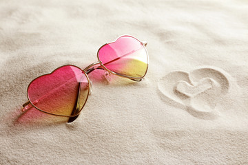 Glasses in shape of heart on white sand