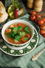 Vegetable soup, Uzbek shurpa soup on a green napkin, with cherry tomatoes and bread pita