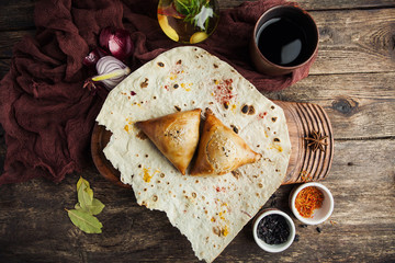 Asian Uzbek samsa dish with meat on pita bread with a glass of wine with spices on a wooden table