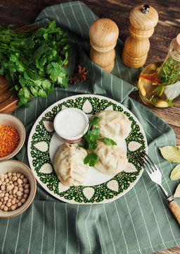 Asian Uzbek manti dish with sour cream on a green napkin with chickpeas and spices