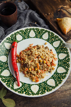 Asian Uzbek dish pilaf with chickpeas and meat and samsa on a wooden table