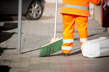 Horizontal View of a Dustman Cleaning the Street With a Mop Wearing an Orange Uniform