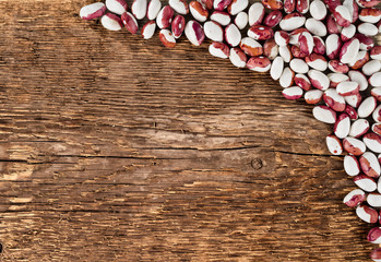 Spotted kidney beans on a background of rough wooden texture.
