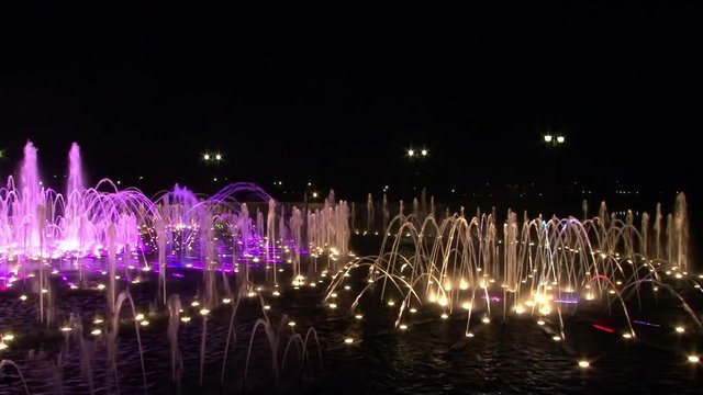 Dancing fountains of ultraviolet colors in Moscow at night. Beautiful views of capital of Russia. Bright colorful water on black sky background in big city.