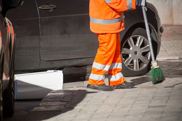 Horizontal View of a Dustman Cleaning the Street With a Mop Wearing an Orange Uniform